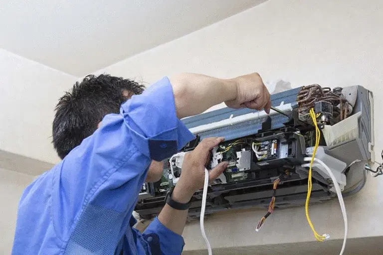 Technician repairing wall-mounted split air conditioner, AC repair service in Dubai, air conditioning maintenance and wiring fix