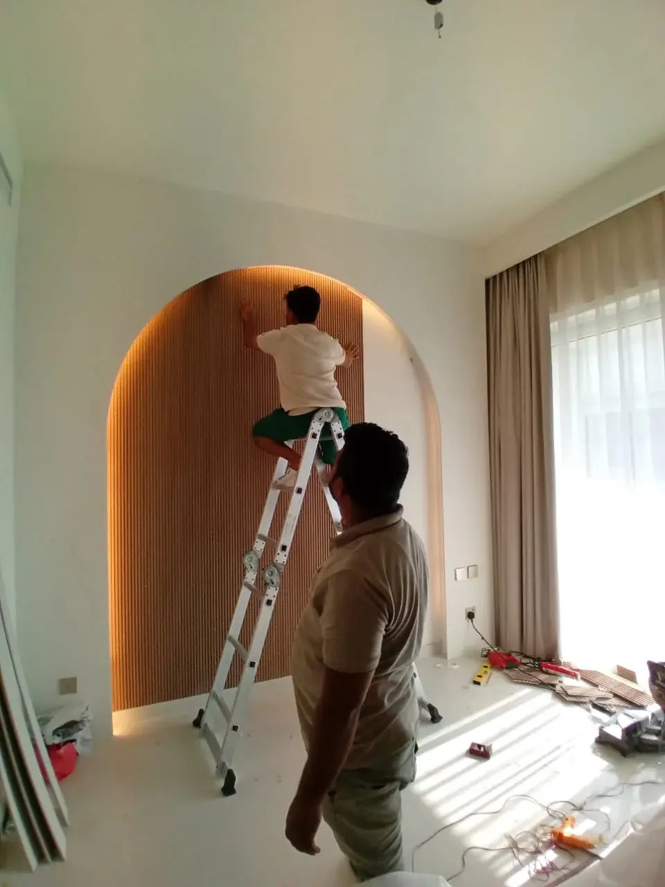 Workers installing wooden architectural panel in a room, home service company in Dubai.